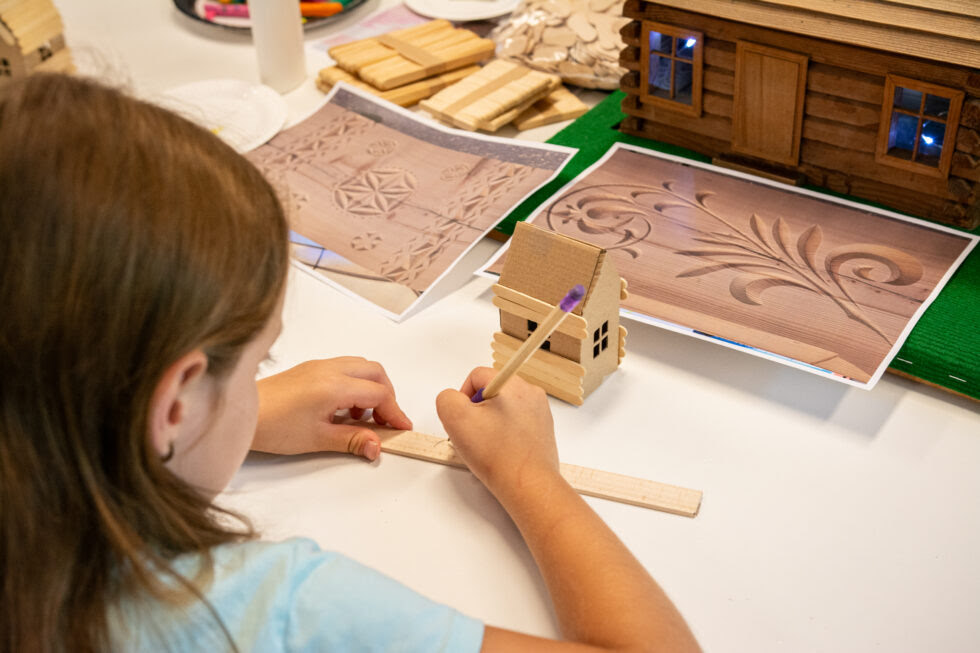 zdjęcie przedstawia dziecko budujące drewniany dom z patyczków - warsztaty dzień architektury drewnianej